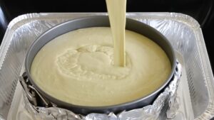 Smooth Pistachio Cream Being Poured Into a Foil-Wrapped Springform Pan Placed in A Water Bath