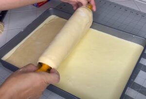 A rolling pin glides over a creamy