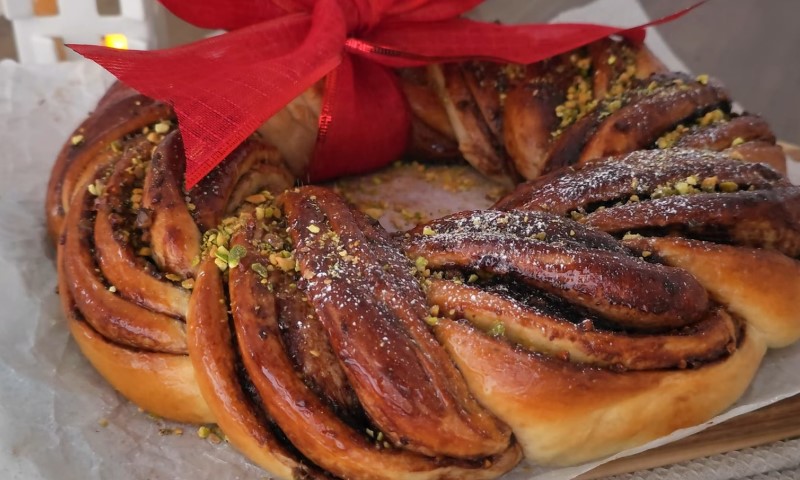 Braided bread wreath topped with pistachios and dusted with sugar
