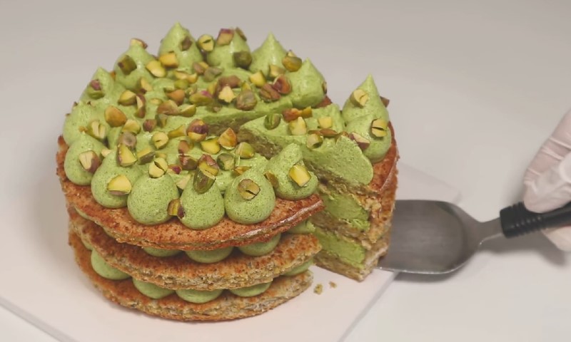 Layered pistachio cake with vibrant green frosting and chopped pistachios