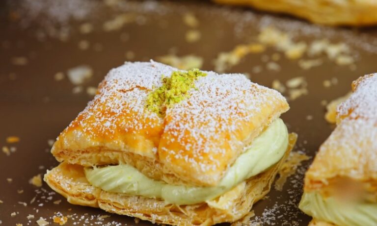 Flaky pastry with creamy green pistachio filling, dusted with powdered sugar.